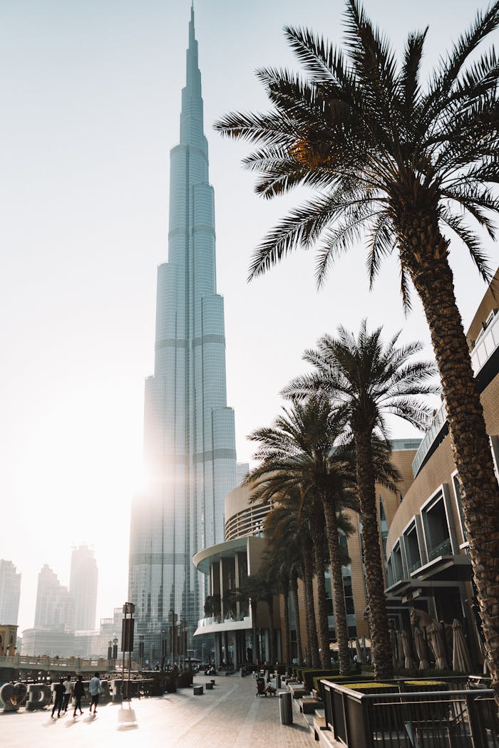 Sunlit view of Burj Khalifa surrounded by palm trees and modern architecture in Dubai.