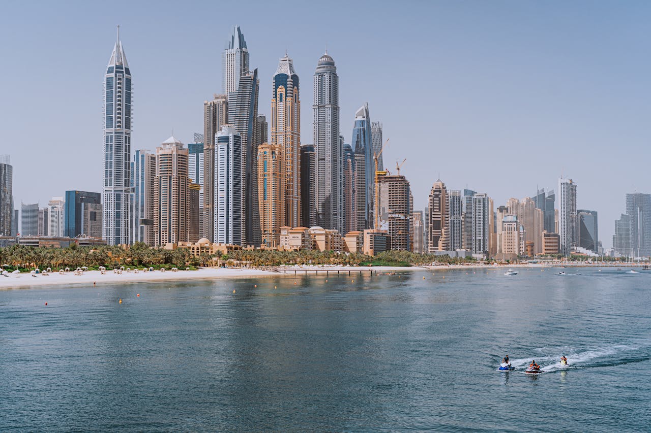 Explore the iconic Dubai Marina skyline with beachfront and water activities under a clear blue sky.